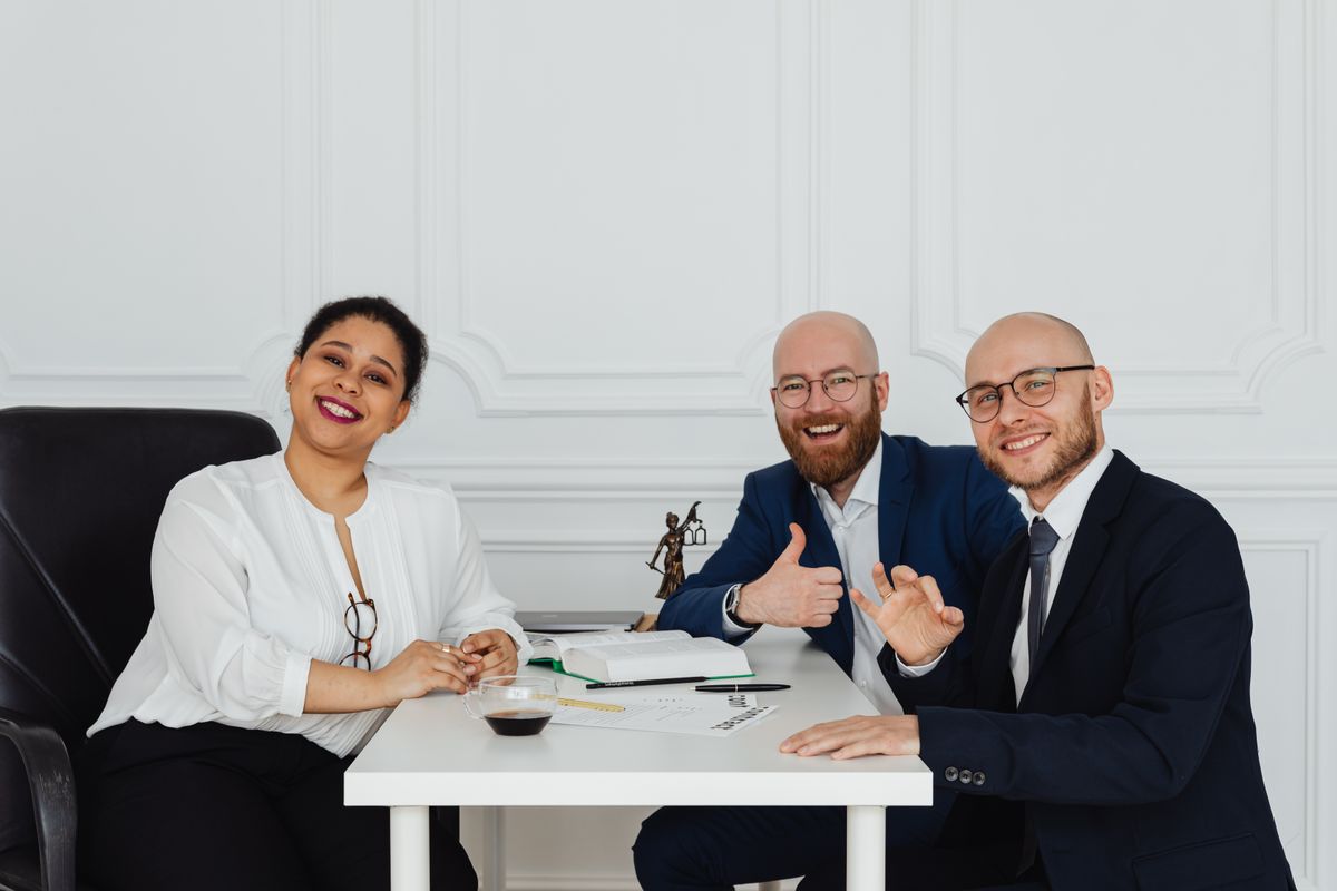 Advogados do escritório reunidos, com uma estátua da Justiça sobre a mesa